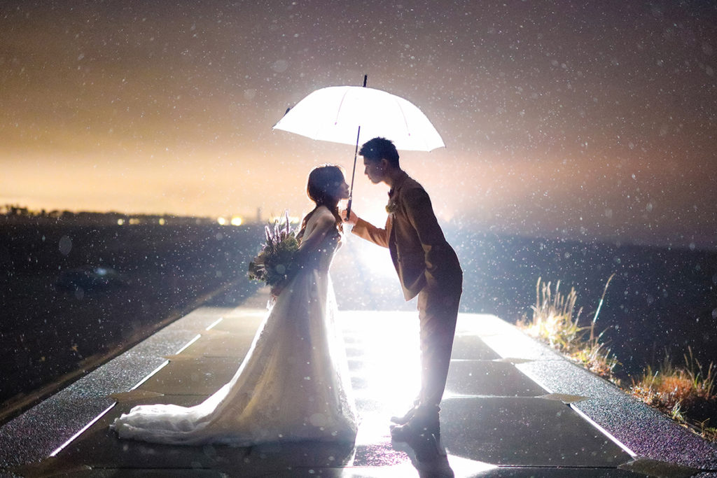 雨の夕暮れで相合い傘　向かい合う新郎新婦　ロマンチックフォト