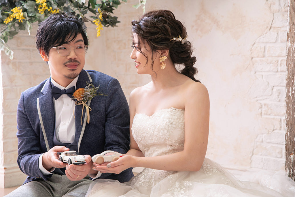 ミニカーを手に持つ笑顔の新郎新婦