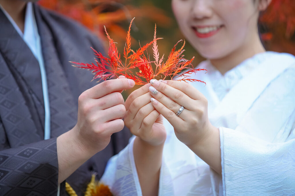 リングやネイルが見えるお手元ショット、お二人で紅葉の葉っぱを持って