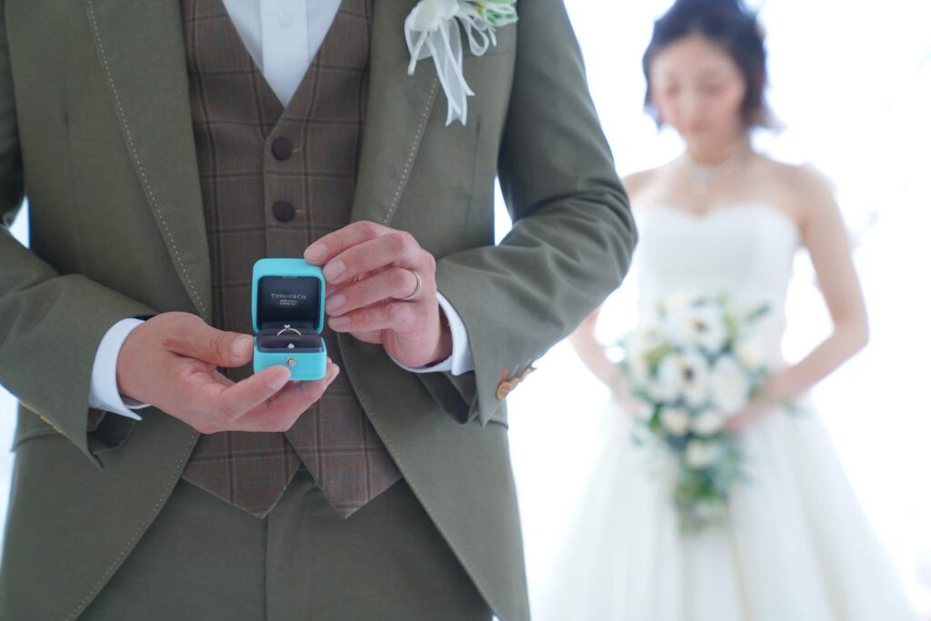 持ち込みのリングBOXを開けた花婿手元と、後ろで待つ花嫁