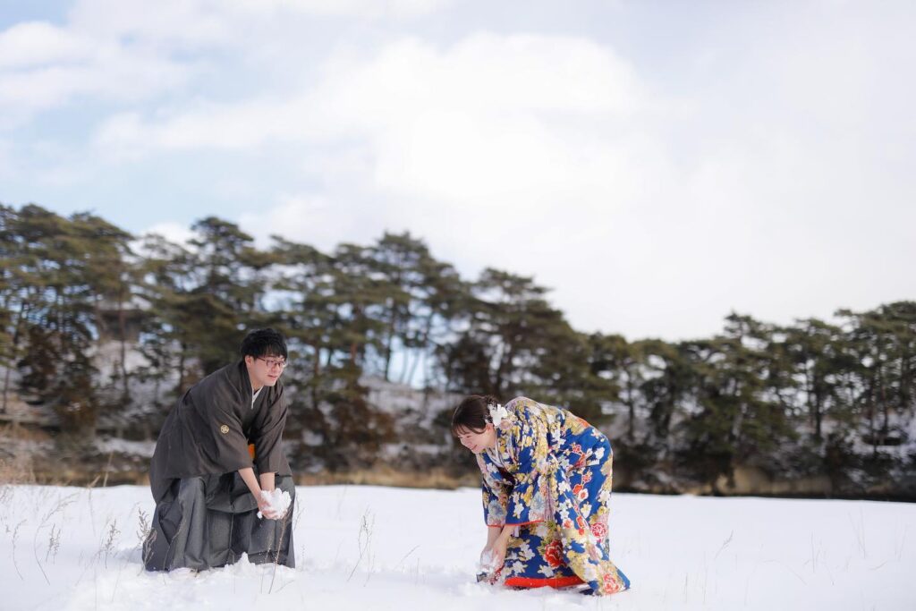 雪が積もった松島で、手に雪を持つ和装姿の新郎新婦