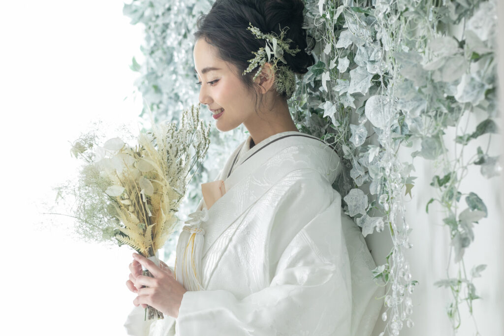 白っぽい空間で笑顔の白無垢花嫁の横顔
